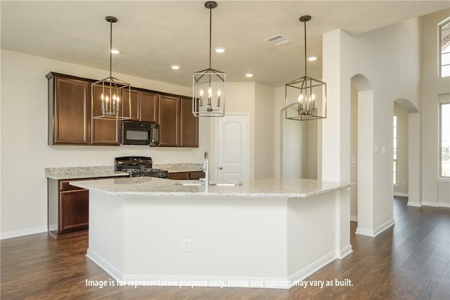 kitchen with dark hardwood / wood-style flooring, sink, an island with sink, and black appliances