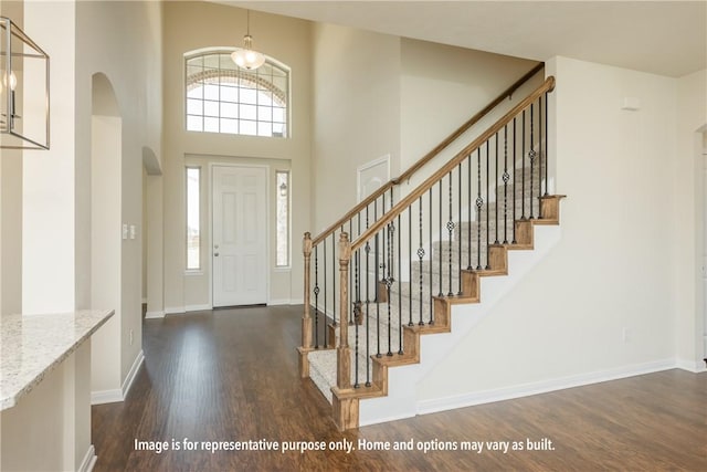 foyer entrance featuring dark hardwood / wood-style flooring and a towering ceiling