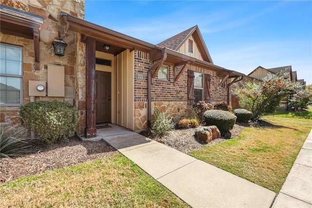 view of exterior entry with stone siding and a lawn