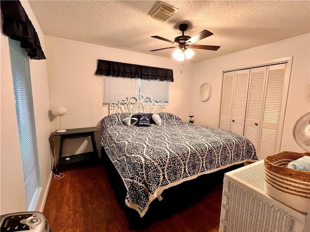 bedroom with a textured ceiling, a closet, dark hardwood / wood-style floors, and ceiling fan