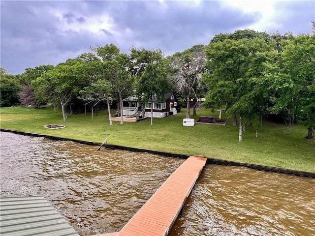 view of dock featuring a lawn and a water view