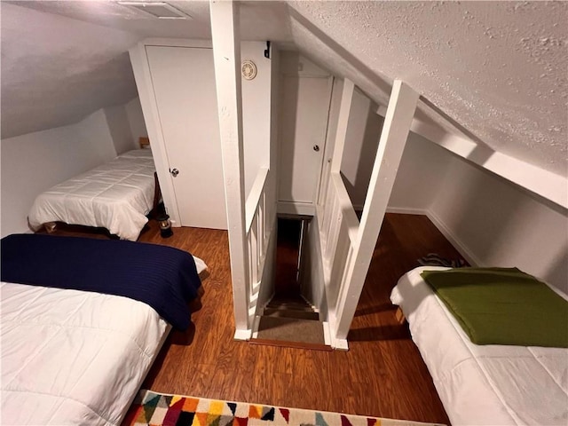 bedroom with wood-type flooring, a textured ceiling, and lofted ceiling