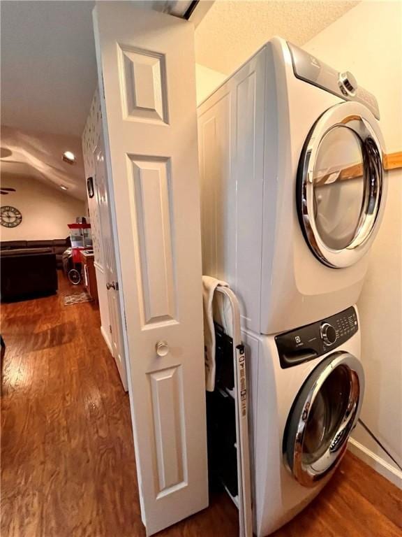 washroom with dark hardwood / wood-style flooring and stacked washing maching and dryer