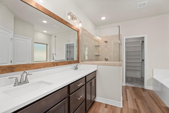 3008 Alpha Ct, Bryan, TX 77808 - bathroom with double vanity, a walk in closet, a bath, tiled shower, and wood finished floors