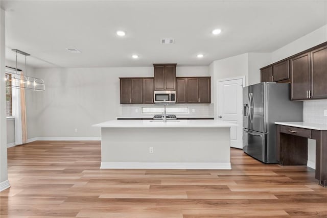 3008 Alpha Ct, Bryan, TX 77808 - kitchen featuring stainless steel appliances, light countertops, light wood-type flooring, dark brown cabinets, and backsplash
