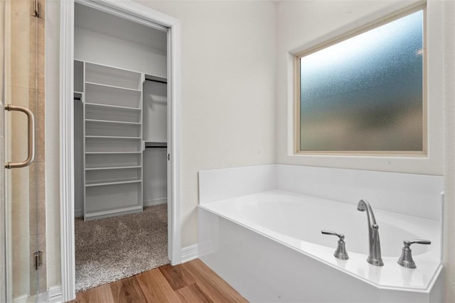 3008 Alpha Ct, Bryan, TX 77808 - bathroom with a spacious closet, a bath, wood finished floors, a stall shower, and baseboards