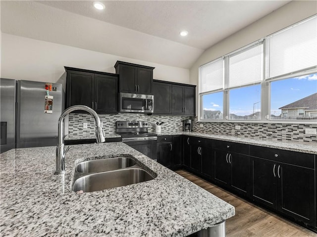 kitchen featuring lofted ceiling, backsplash, sink, appliances with stainless steel finishes, and wood-type flooring