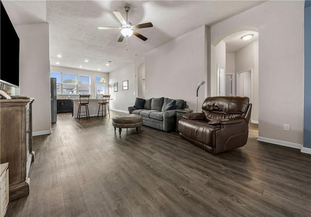 living room featuring a textured ceiling, ceiling fan, and dark wood-type flooring