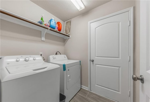 laundry room featuring separate washer and dryer, a textured ceiling, and hardwood / wood-style flooring