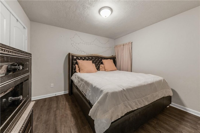 bedroom with dark hardwood / wood-style floors and a textured ceiling