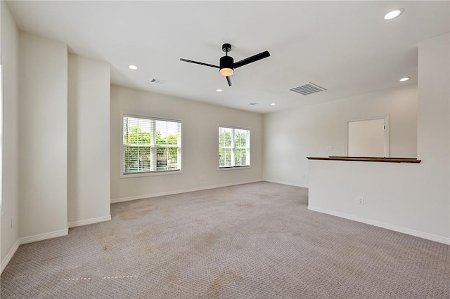 empty room with visible vents, light colored carpet, and ceiling fan