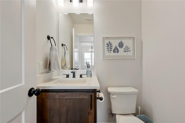 half bath featuring visible vents, vanity, and toilet