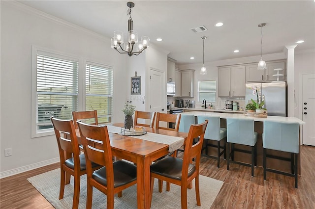 dining room featuring a wealth of natural light, ornamental molding, wood finished floors, and visible vents