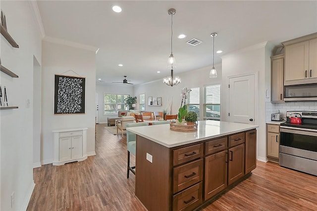 kitchen featuring visible vents, wood finished floors, light countertops, a breakfast bar, and appliances with stainless steel finishes
