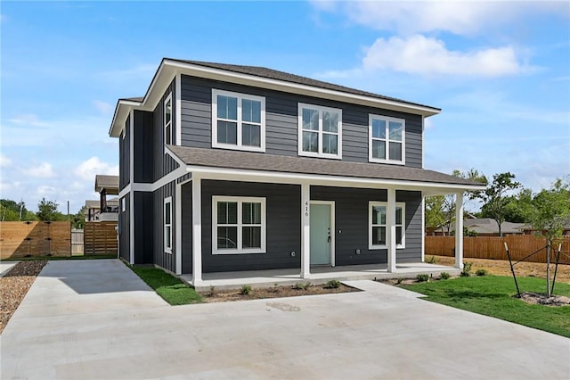traditional-style house featuring a porch, concrete driveway, fence, and a shingled roof