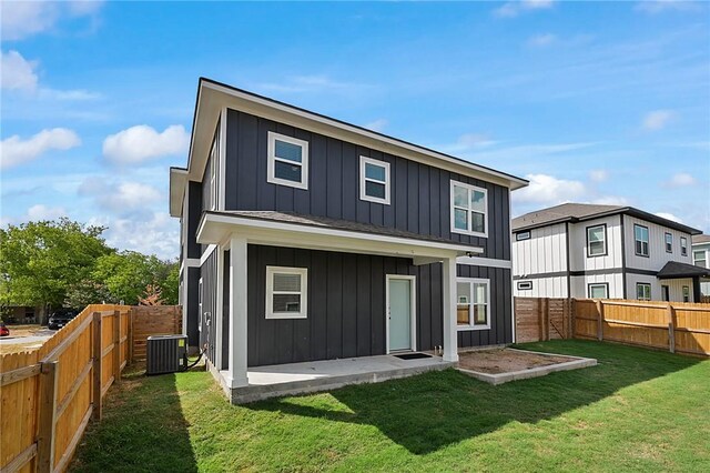 back of house with board and batten siding, a yard, a patio area, and a fenced backyard