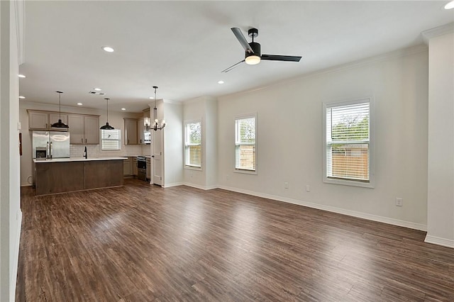 unfurnished living room featuring ceiling fan with notable chandelier, dark wood finished floors, baseboards, ornamental molding, and recessed lighting