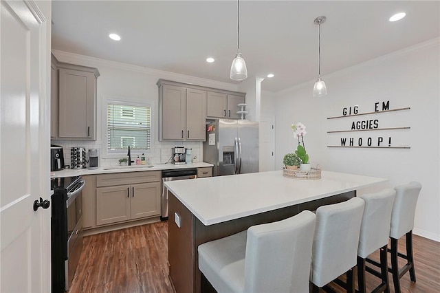 kitchen with appliances with stainless steel finishes, a breakfast bar area, gray cabinetry, and a sink