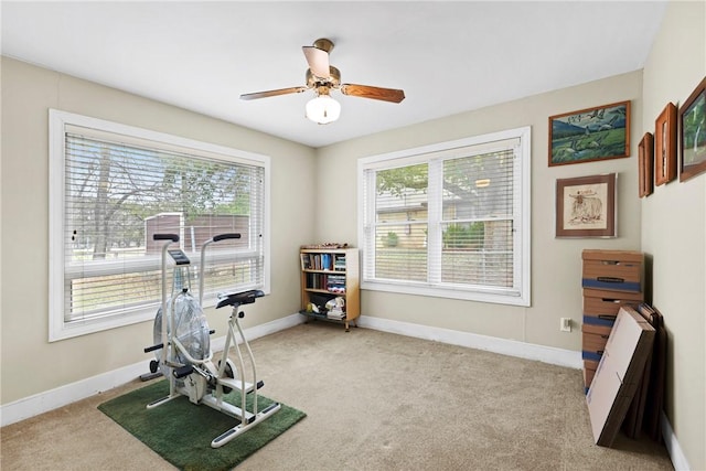 exercise room featuring light carpet, ceiling fan, and baseboards