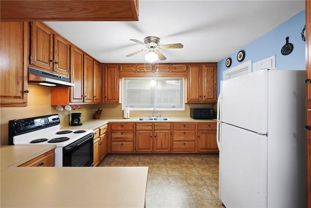 kitchen featuring under cabinet range hood, a sink, light countertops, freestanding refrigerator, and electric range oven