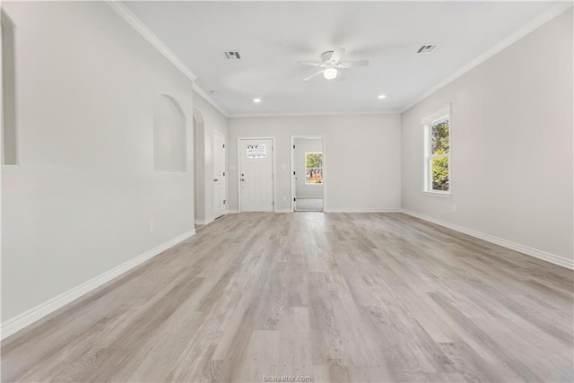empty room featuring arched walkways, ceiling fan, ornamental molding, and visible vents
