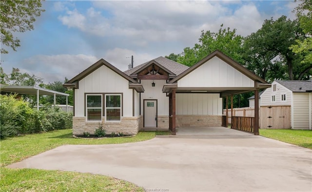 view of front of home with fence, driveway, a front lawn, and stone siding