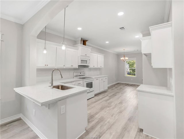 kitchen featuring a sink, white appliances, a peninsula, white cabinetry, and visible vents