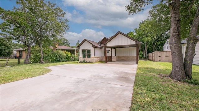 ranch-style house with a carport, stone siding, a front yard, and concrete driveway
