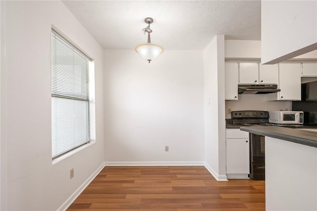 4441 Old College Rd, Bryan, TX 77801 - kitchen featuring black range with electric cooktop, white microwave, dark countertops, and light wood-type flooring