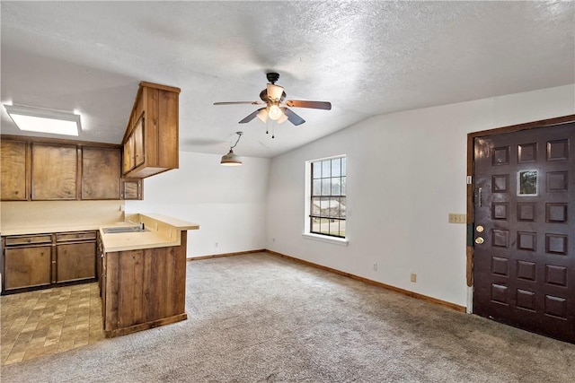 kitchen with sink, vaulted ceiling, light colored carpet, and kitchen peninsula