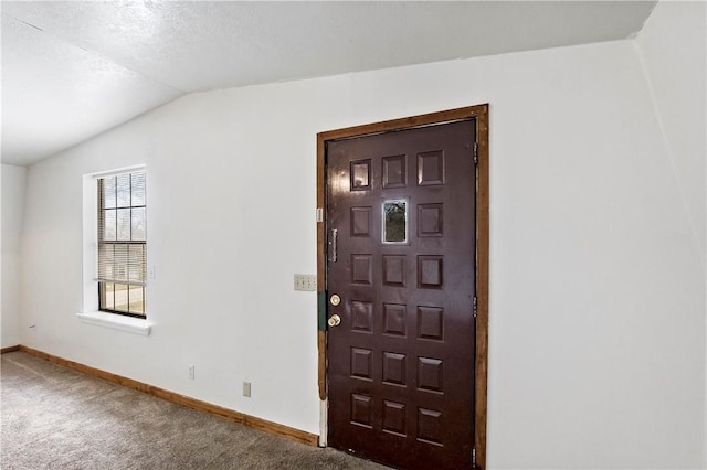 carpeted foyer with a textured ceiling and vaulted ceiling