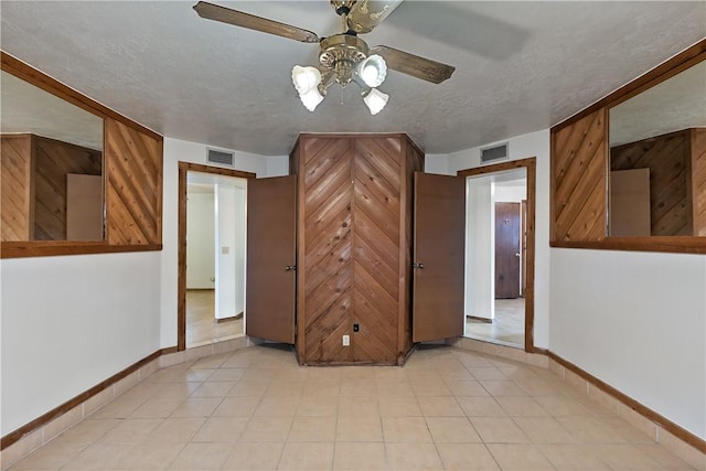 spare room featuring ceiling fan, wood walls, and a textured ceiling