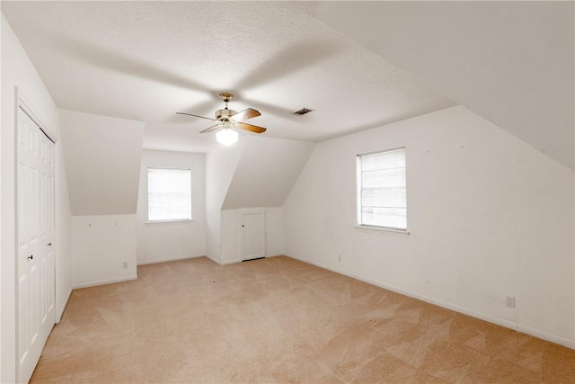 bonus room with vaulted ceiling, light colored carpet, a textured ceiling, and ceiling fan