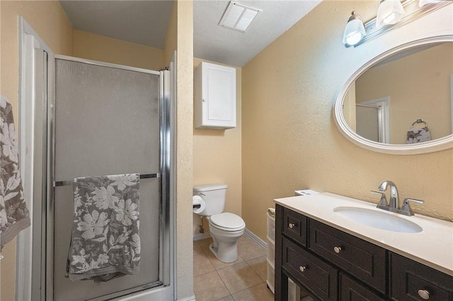 bathroom with tile patterned floors, toilet, a shower with door, and vanity