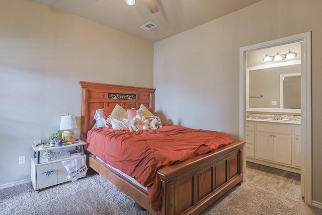 carpeted bedroom with sink and ensuite bath