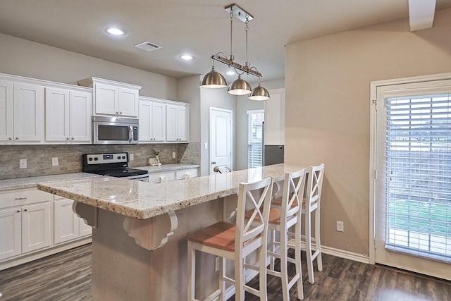 kitchen with appliances with stainless steel finishes, a breakfast bar, and white cabinets