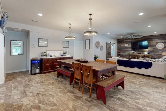 dining area featuring a barn door, visible vents, wine cooler, wood walls, and recessed lighting