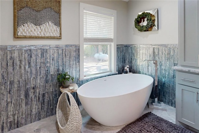 bathroom featuring a freestanding tub, wainscoting, and tile walls