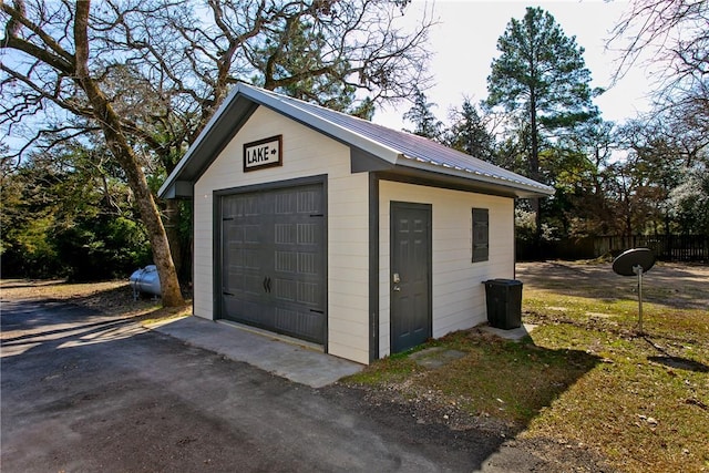 detached garage featuring aphalt driveway and fence