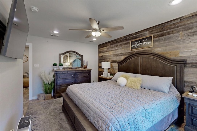 bedroom with visible vents, carpet flooring, wood walls, ceiling fan, and baseboards