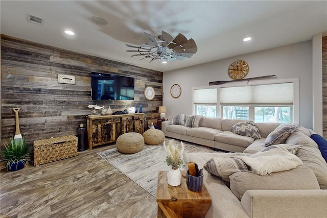 living room featuring wooden walls, visible vents, ceiling fan, an accent wall, and recessed lighting