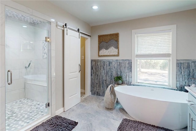 full bathroom with recessed lighting, tile walls, wainscoting, a soaking tub, and a stall shower