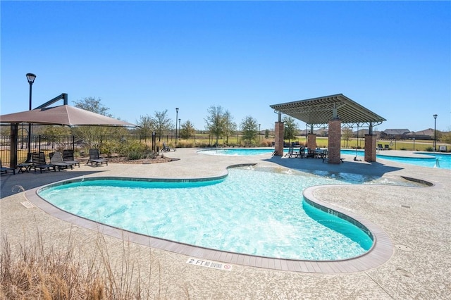 community pool with fence, a gazebo, and a patio area