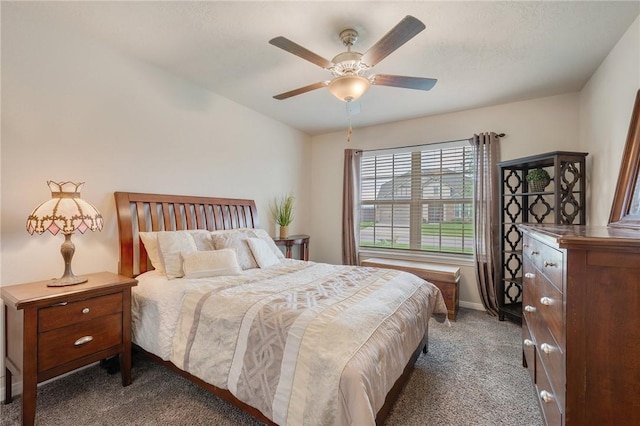 bedroom featuring baseboards, dark colored carpet, and ceiling fan