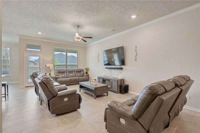 living area featuring baseboards, a ceiling fan, a textured ceiling, and crown molding