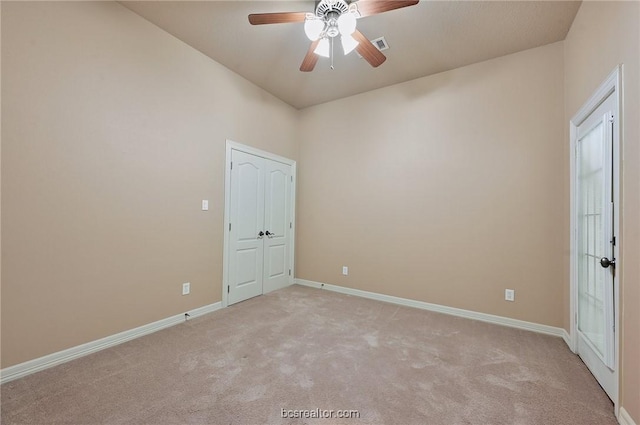 empty room featuring ceiling fan and light colored carpet