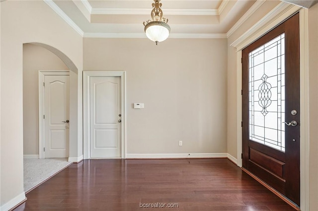 foyer with a tray ceiling, dark wood-type flooring, and ornamental molding