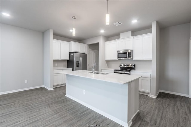 kitchen with appliances with stainless steel finishes, white cabinetry, an island with sink, sink, and hanging light fixtures