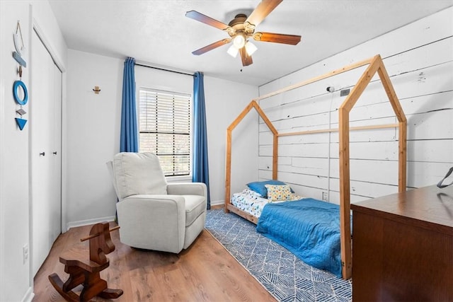 bedroom with ceiling fan, wood-type flooring, and a closet