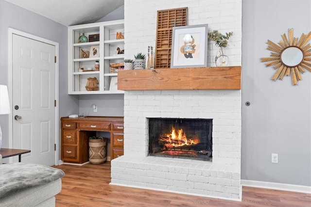 living room with a fireplace, wood-type flooring, and vaulted ceiling